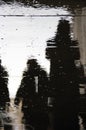 Portrait image of the reflection on pavement of a group of people walking