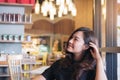 Portrait image of a smiley beautiful Asian woman with feeling good sitting and relaxing in modern cafe Royalty Free Stock Photo