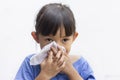 A little girl blowing her runny nose by tissue paper.