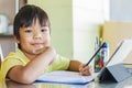 Asian student child boy using and touching smart pad or tablet for do his homework and online learning E-learning. Royalty Free Stock Photo
