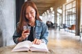 A young beautiful asian woman drinking coffee and reading book Royalty Free Stock Photo