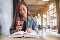 A young beautiful asian woman drinking coffee and reading book Royalty Free Stock Photo
