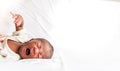 African 12-day-old baby black skin newborn son, lying on a white bed and is crying Royalty Free Stock Photo