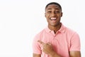 Portrait of impressed delighted and surprised charismatic handsome african american young male in pink shirt pointing