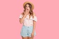 Portrait of impressed surprised model isolated over pink background in studio, covering her mouth with hand, opening her mouth and