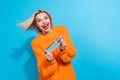 Portrait of impressed woman fluttering hair dressed knitwear sweater hold smartphone play excited game isolated on blue