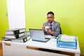 Portrait of Indian Businessman holding mug and working on his laptop computer at his desk