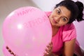 Portrait of an indian girl dressed in pink dress with pink balloons on her birthday with selective focus on balloon