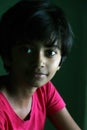 Portrait of an Indian little girl with short hair. Beautiful eye of a child on black background. Dramatic look of a little girl in