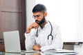 Portrait of indian man doctor talking to online patient on laptop online consultation Royalty Free Stock Photo