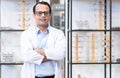 Portrait of Indian middle aged ophthalmologist or optometrist man work at optometry clinic, crossed arms standing in front of