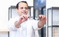 Portrait of Indian middle aged ophthalmologist or optometrist man work at optometry clinic, holding and showing new collection of