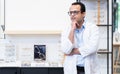 Portrait of Indian middle aged ophthalmologist or optometrist man work at optometry clinic, thinking and standing in front of new