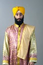 Portrait of Indian sikh man with bushy beard standing against a grey background