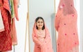 Portrait Indian teenage cute girl standing front mirror at home in living room, joyful choosing, dressing up traditional clothes Royalty Free Stock Photo