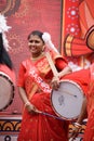 Portrait of an Indian woman wearing a traditional Bengali outfit and playing Dhak Dhol at a puja pandal on the last day of Durga