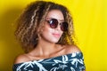 Portrait indoors of a young afro american woman in sunglasses. Yellow background. Lifestyle. Casual clothing Royalty Free Stock Photo