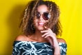 Portrait indoors of a young afro american woman in sunglasses. Yellow background. Lifestyle. Casual clothing Royalty Free Stock Photo