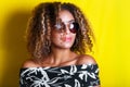 Portrait indoors of a young afro american woman in sunglasses. Yellow background. Lifestyle. Casual clothing Royalty Free Stock Photo