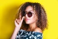 Portrait indoors of a young afro american woman in sunglasses. Yellow background. Lifestyle. Casual clothing Royalty Free Stock Photo