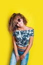 Portrait of a young afro american woman in sunglasses. Yellow background. Lifestyle.