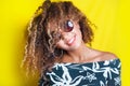 Portrait of a young afro american woman in sunglasses. Yellow background. Lifestyle.