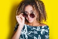 Portrait of a young afro american woman in sunglasses. Yellow background. Lifestyle. Royalty Free Stock Photo