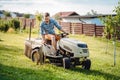 Portrait of Industrial gardener driving a riding lawn mower in in a garden. Royalty Free Stock Photo