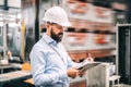 A portrait of an industrial man engineer with clipboard in a factory, writing.