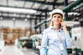 A portrait of an industrial woman engineer standing in a factory, making a phone call. Royalty Free Stock Photo