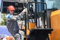 Portrait industrial worker driver in helmet and headphones against background of excavator. People mining concept