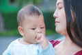 Portrait of infant baby boy is sucking hand with Asian mother carrying Royalty Free Stock Photo