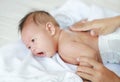 Portrait of infant baby lying on the bed with mother hands applying a lotion cream Royalty Free Stock Photo