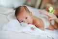 Portrait of infant baby lying on the bed with mother hands applying a lotion cream Royalty Free Stock Photo