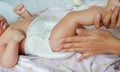 Portrait of infant baby lying on the bed with mother hands applying a lotion cream Royalty Free Stock Photo