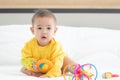 Portrait innocent baby child holding and playing toy on white bed in bedroom with bright soft light in morning in background Royalty Free Stock Photo