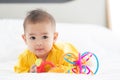 Portrait innocent baby child holding and playing toy on white bed in bedroom with bright soft light in morning in background Royalty Free Stock Photo