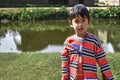 Portrait of An innocent poor boy of India standing on a ponds side and looking at camera, wearing the traditional dress