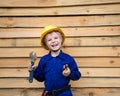 Portrait of inquisitive boy 6 years old in a blue overalls uniform and in a construction helmet with tools in his hands Royalty Free Stock Photo