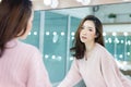 Portrait of inspired caucasian Asian lady wearing knitted sweater pink with beautiful makeup looking at camera a mirror in studio