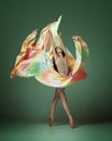 Portrait of inspired gorgeous ballerina, beautiful girl wearing silk dress and dancing with emotion over dark green