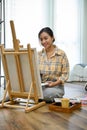 Portrait, Inspired Asian female artist painting with an acrylic color on her empty canvas easel