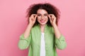 Portrait of intelligent girl with wavy hairdo wear green shirt holding eyewear at vision checkup isolated on pink color Royalty Free Stock Photo