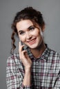 Portrait of an intelligent student with curly hair and with a phone in her hand. Checkered shirt