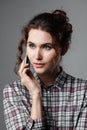 Portrait of an intelligent student with curly hair and with a phone in her hand. Checkered shirt