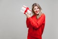 Portrait of interested beautiful blonde woman with red lipstick in bright casual sweater, isolated on gray background