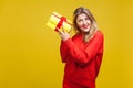 Portrait of interested beautiful blonde woman with red lipstick in bright casual sweater, isolated on yellow background