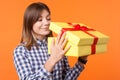 Portrait of interested charming young woman with brown hair unboxing present. isolated on orange background