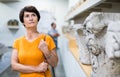 Portrait of interested senior woman visiting museum of ancient sculpture