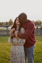 Portrait of interracial couple in love, gently hugging and kissing with eyes closed in nature park Royalty Free Stock Photo